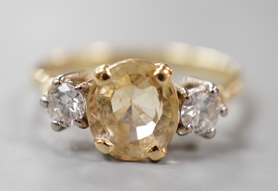 A yellow metal, singe stone oval cut yellow sapphire and two stone round cut diamond set ring, size N/O, gross weight 2.9 grams.